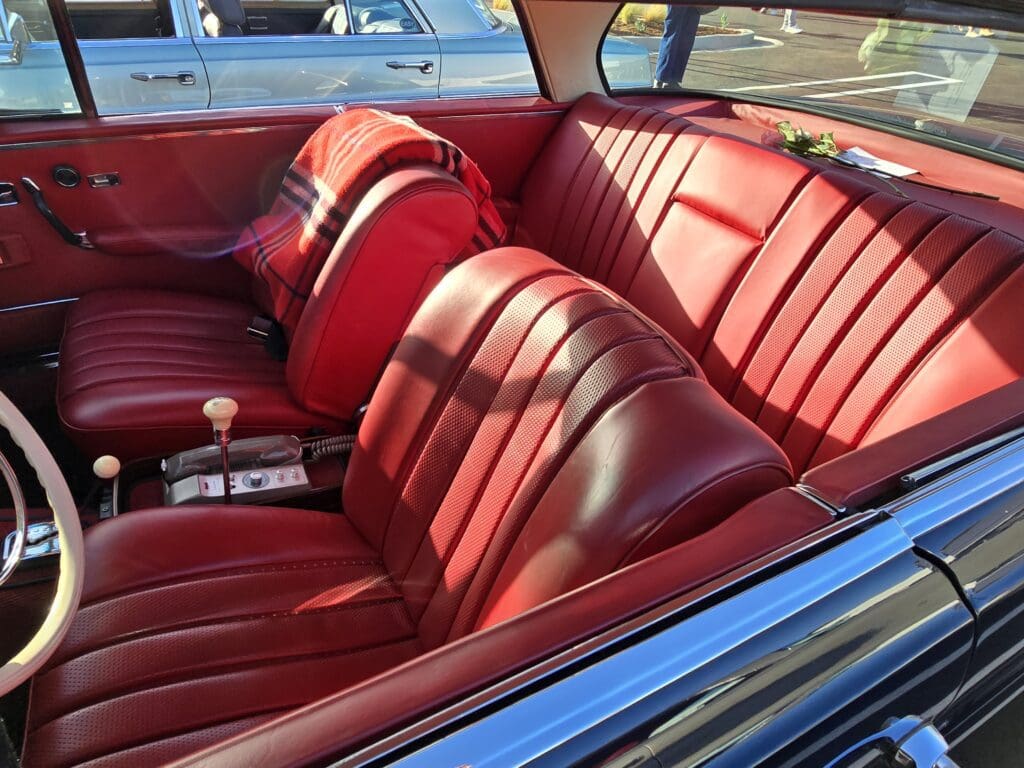 Vintage car interior with red leather seats and chrome accents.