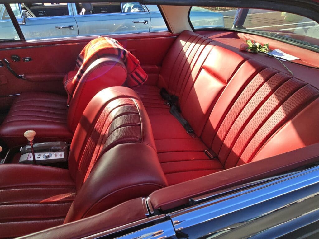 Classic car interior with red leather seats and chrome details.
