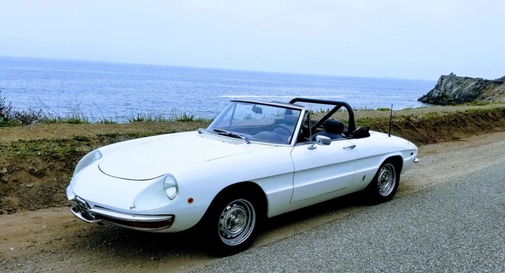 Classic white convertible sports car parked by the seaside.