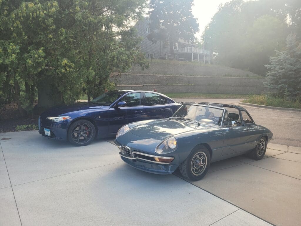 Two classic and modern cars parked side by side in a driveway.