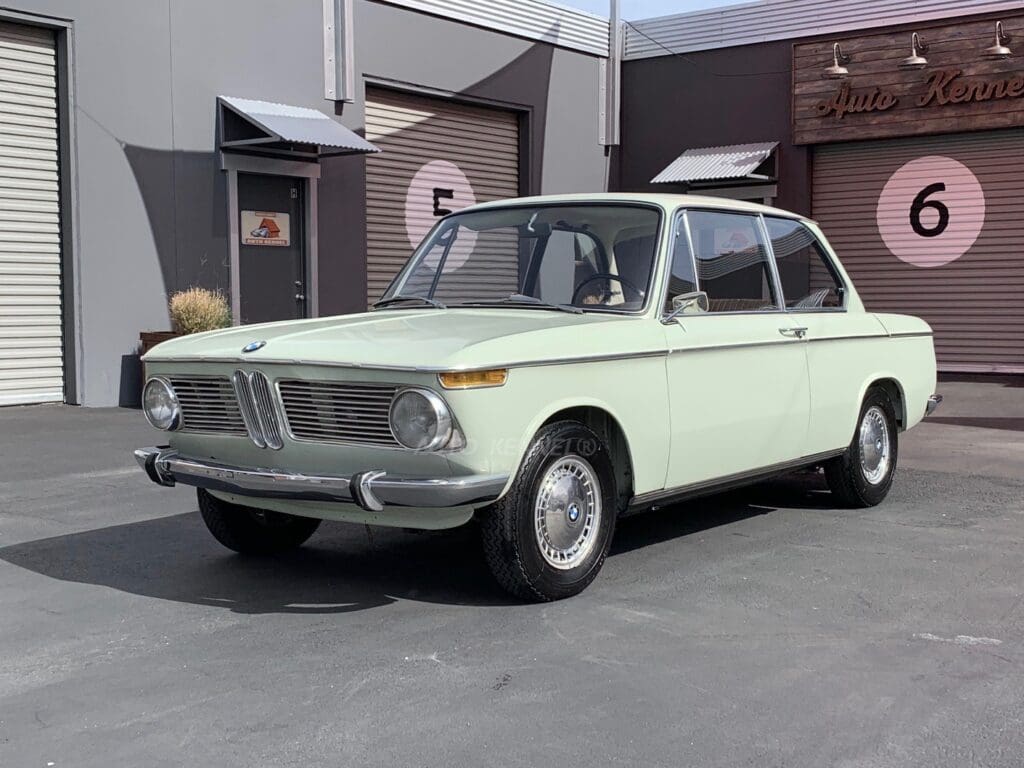 Classic pale green vintage car parked outdoors.