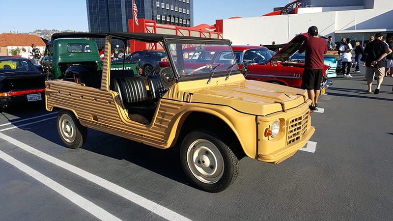 A vintage yellow off-road vehicle parked on a sunny road.