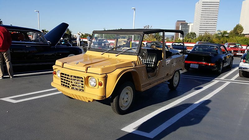 Yellow vintage off-road vehicle parked outdoors on a sunny day.