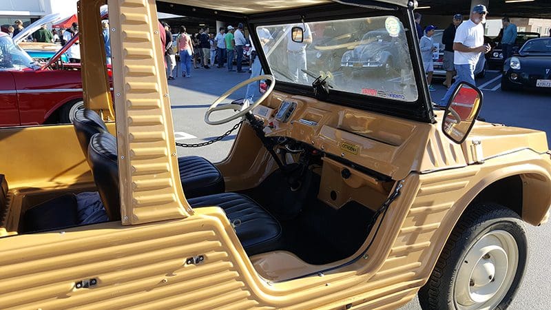 A vintage yellow off-road vehicle parked on a sunny road.