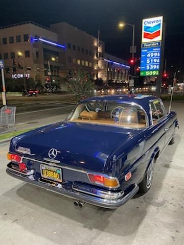 Classic blue Mercedes-Benz parked at a gas station at night.