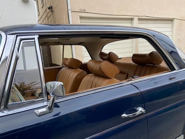 Classic car interior with brown leather seats and door panel.