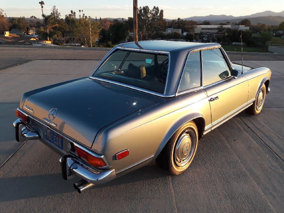 Classic silver two-door coupe parked outdoors during sunset.
