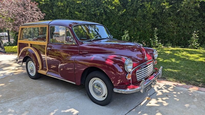 A classic maroon vintage car parked outdoors on a sunny day.