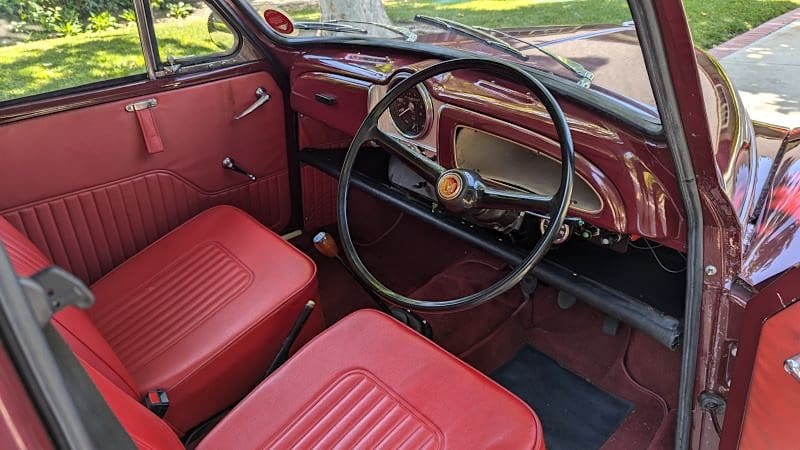 Interior view of a vintage car with red seats and dashboard.