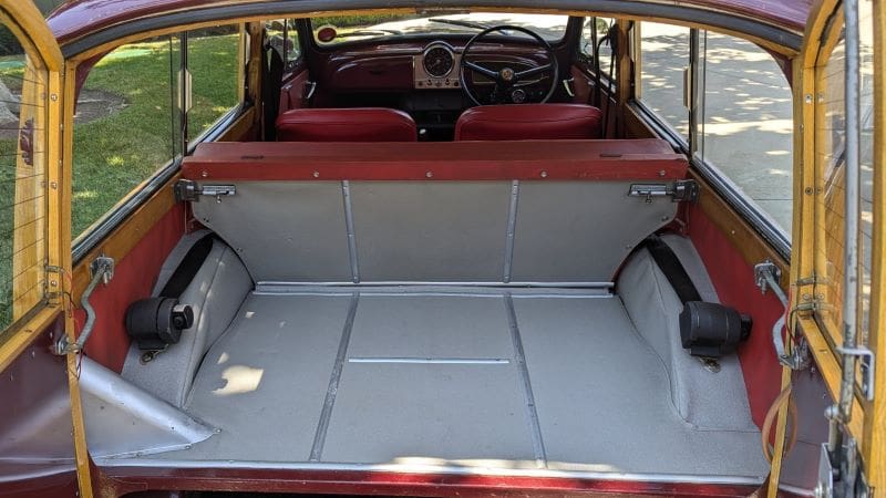 Empty vintage car trunk with red interior and gray lining.