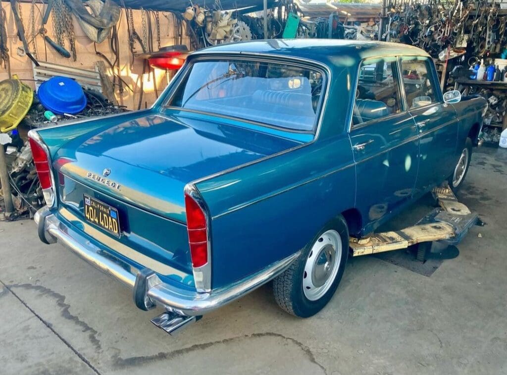 Vintage blue sedan parked outdoors near a blue container.