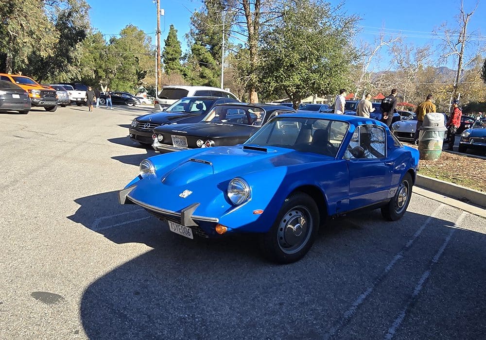 A blue vintage sports car parked next to a black classic car outdoors.
