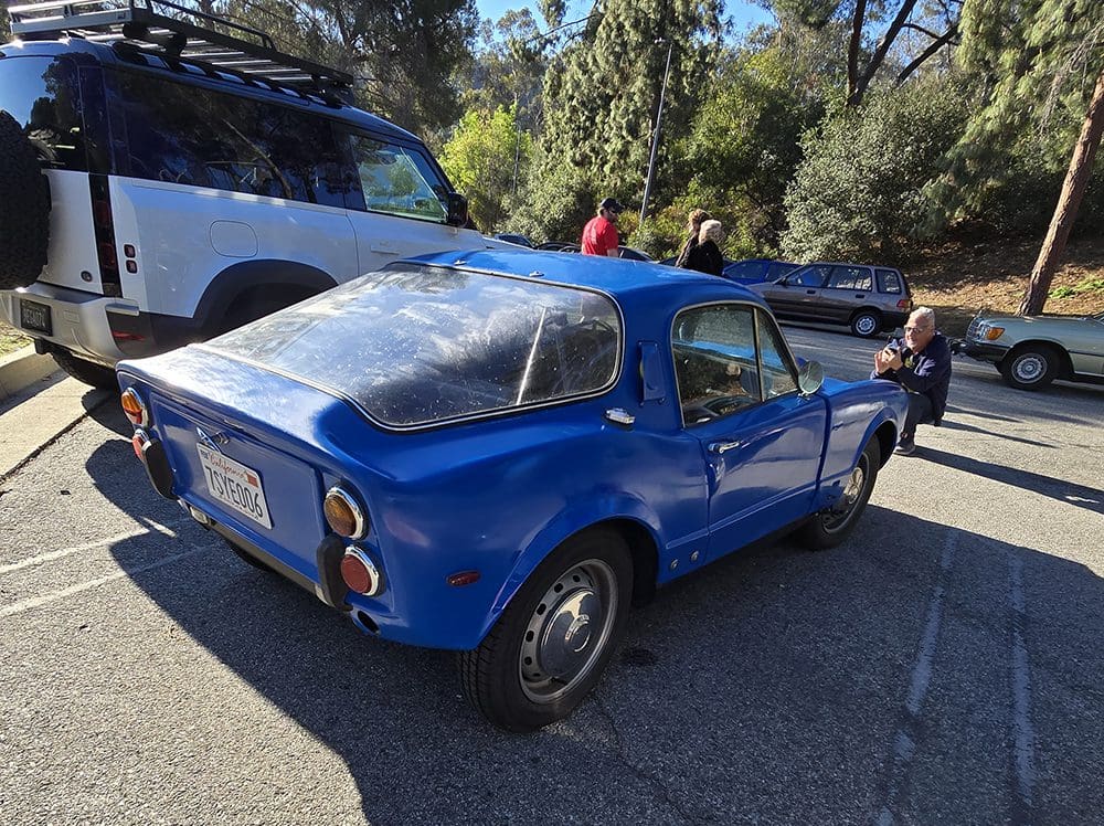 A blue vintage sports car parked outdoors on a sunny day.