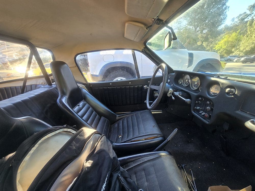 Interior view of a classic car with black leather seats and vintage dashboard.