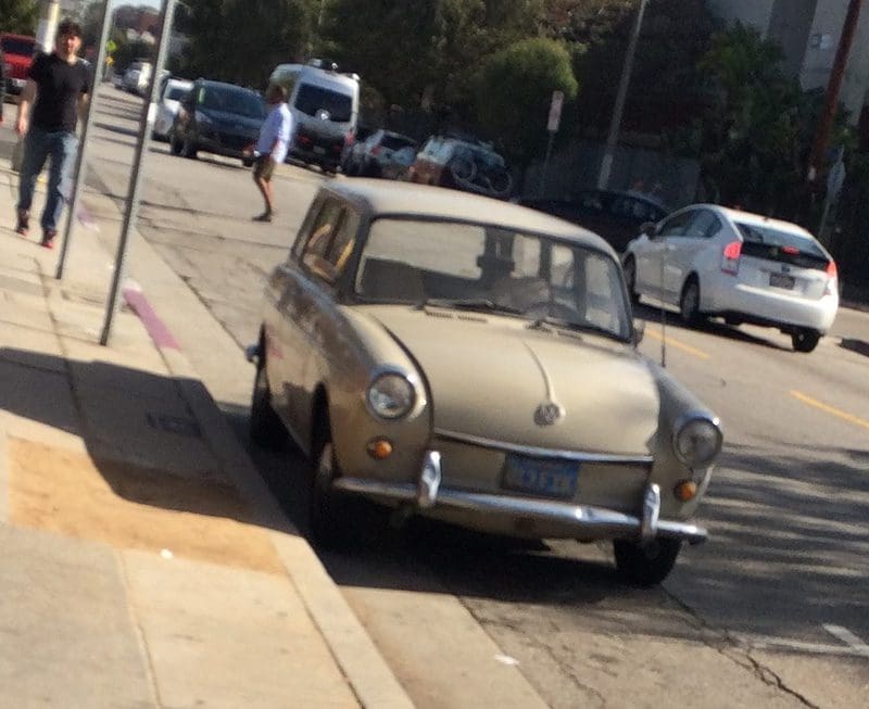 A vintage beige car parked on a sunny street.