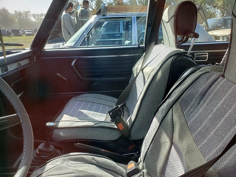 Interior view of a vintage car's backseat with plaid upholstery.