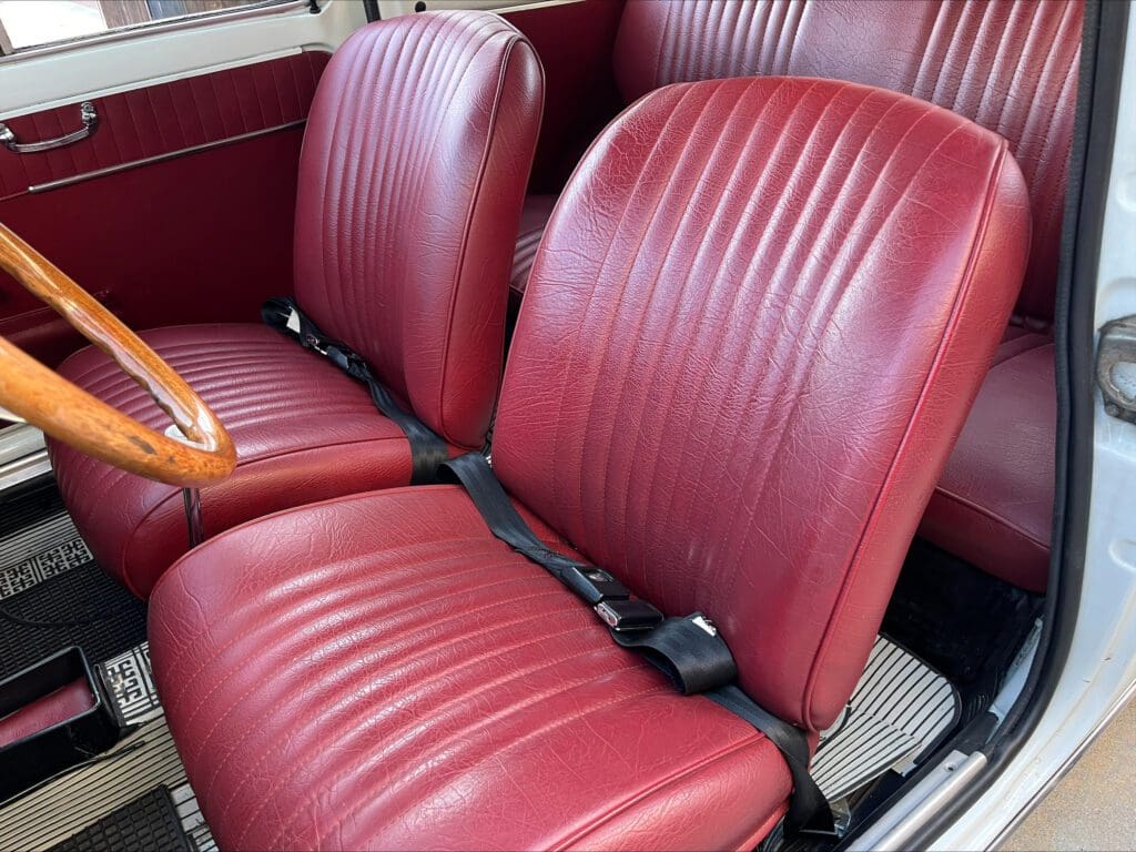 Close-up of vintage red leather car seats with seat belts.