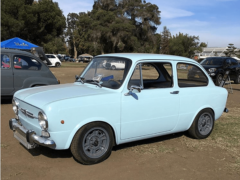 A light blue vintage compact car parked outdoors on a sunny day.