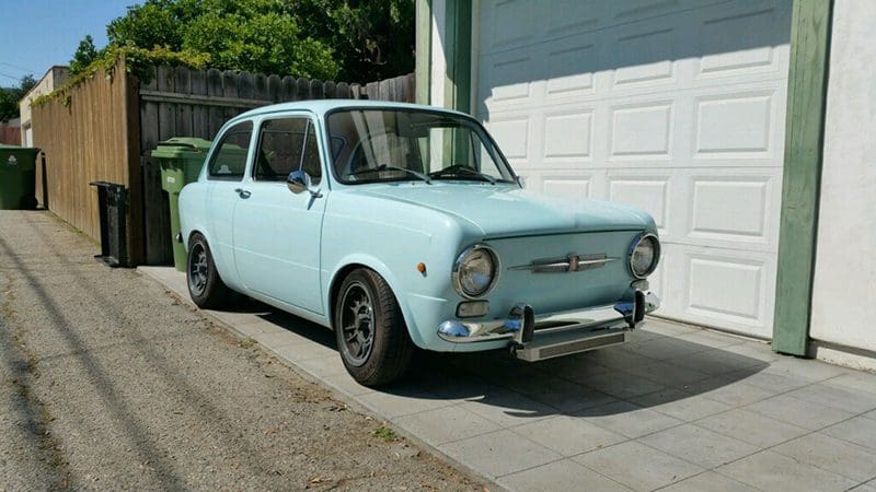 A vintage light blue car parked in a driveway.