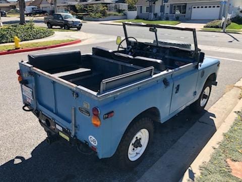 Vintage blue convertible truck parked on a sunny suburban street.