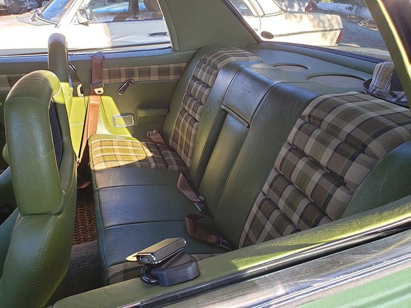 Interior of a vintage car with plaid fabric seats and green door panels.