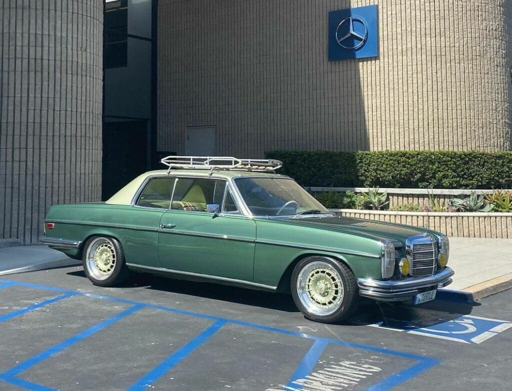 Classic green Mercedes-Benz sedan parked in a handicapped spot.