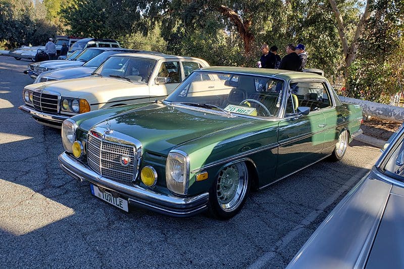 Classic green Mercedes convertible parked outdoors on a sunny day.