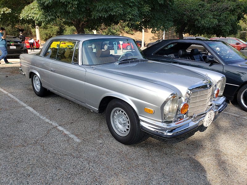 Classic silver vintage car parked outdoors.