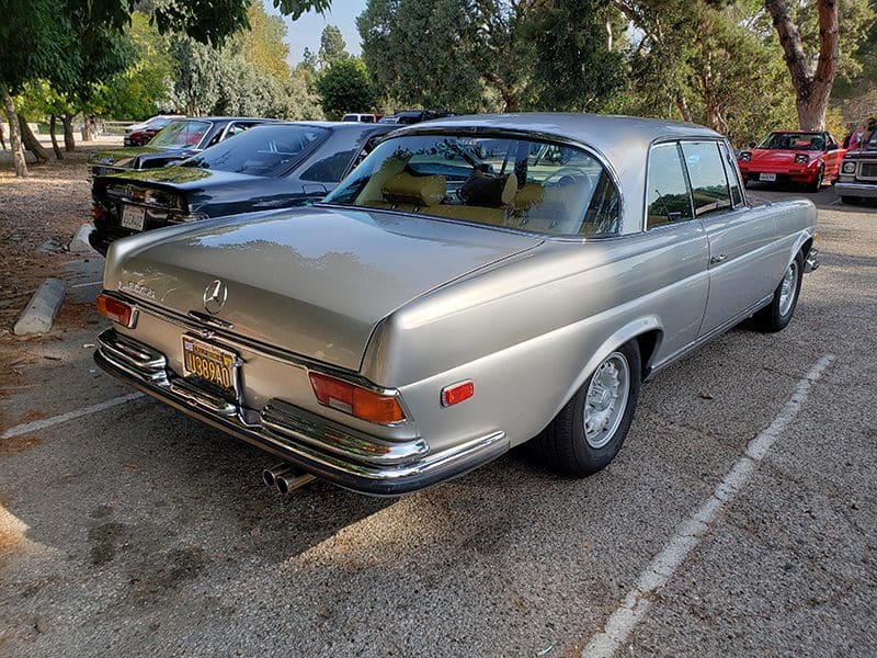 Classic silver Mercedes-Benz parked outdoors among other cars.
