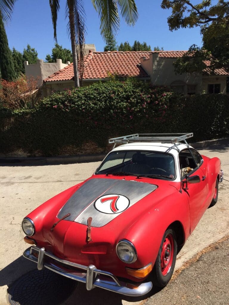 Red vintage convertible car parked on a sunny street.