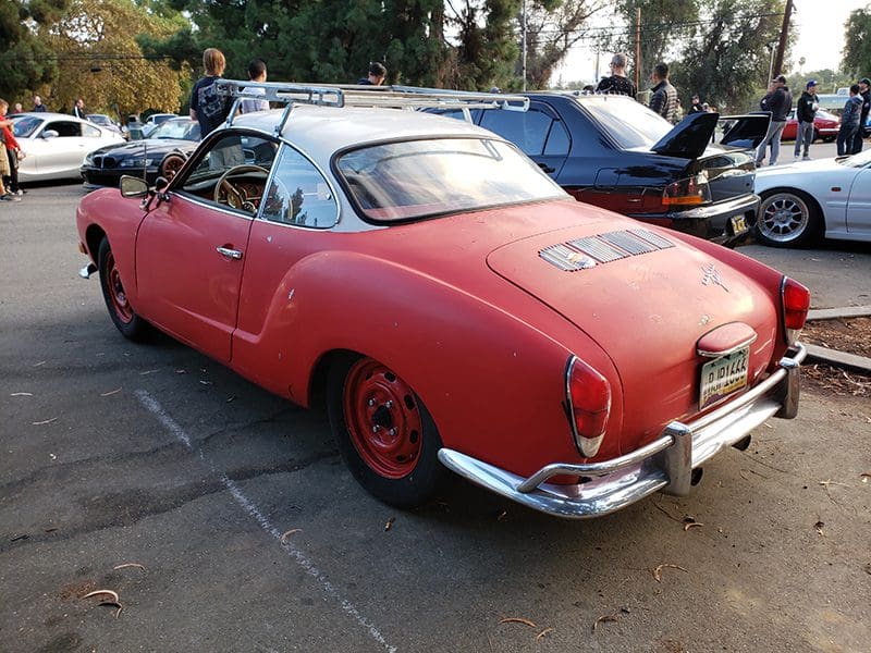 Vintage red sports car parked outdoors with red wheels.