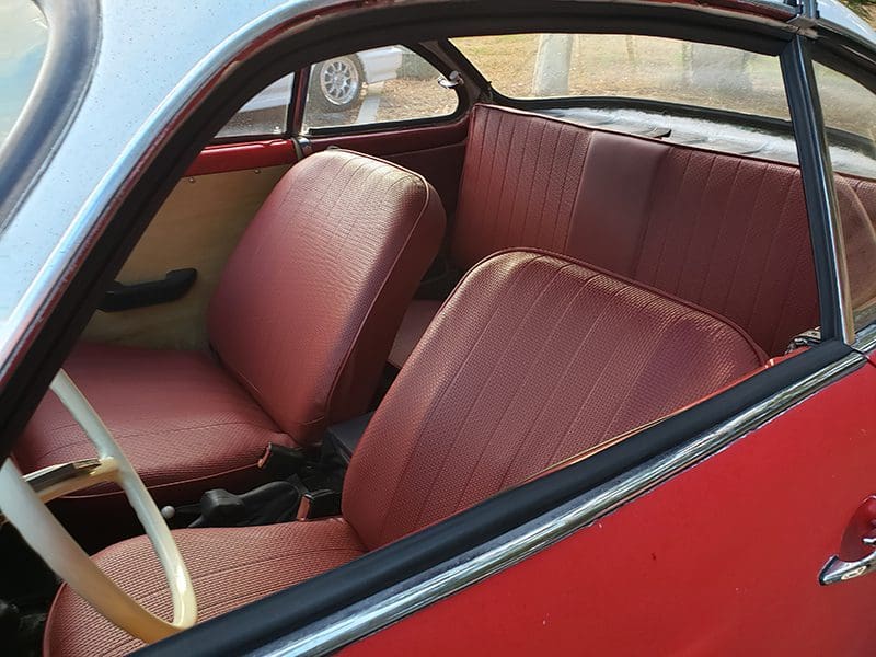 Interior view of a classic red car with red leather seats.