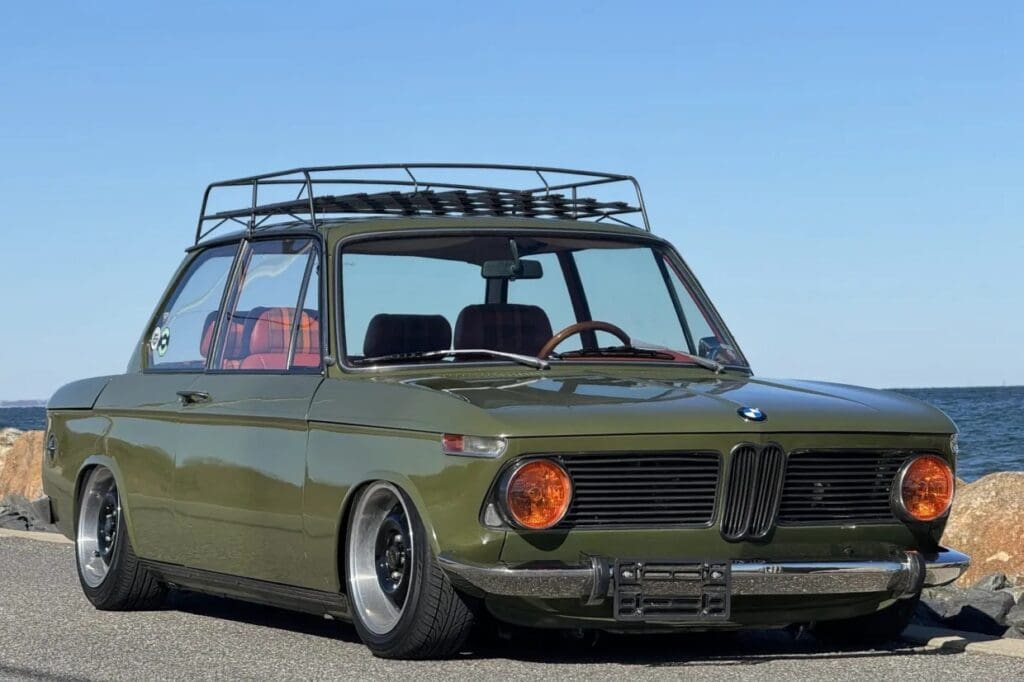 Vintage BMW car with a custom lowered stance and roof rack.