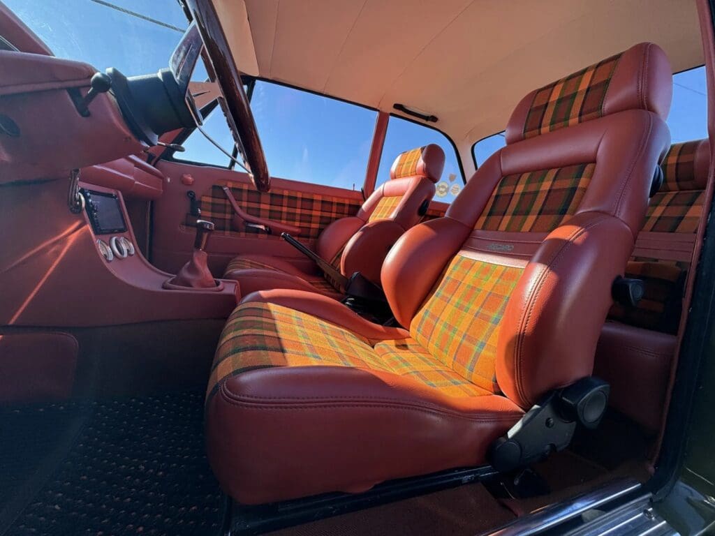Vintage car interior with plaid upholstery and rich red leather seats.