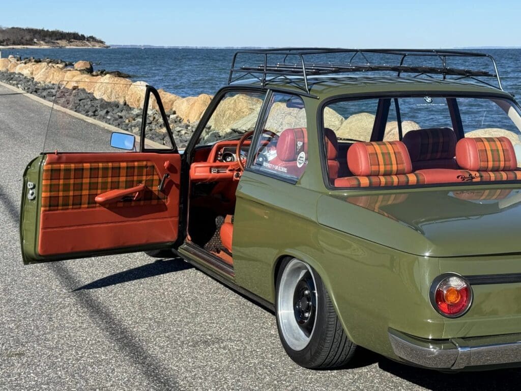 Vintage green car with red checkered interior parked by the seaside.