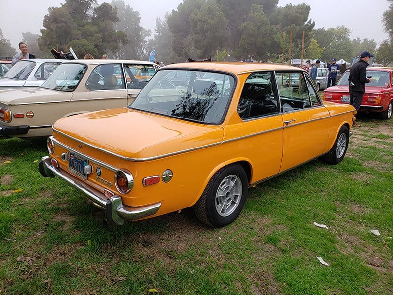 Classic yellow vintage car parked on grass at a car show.