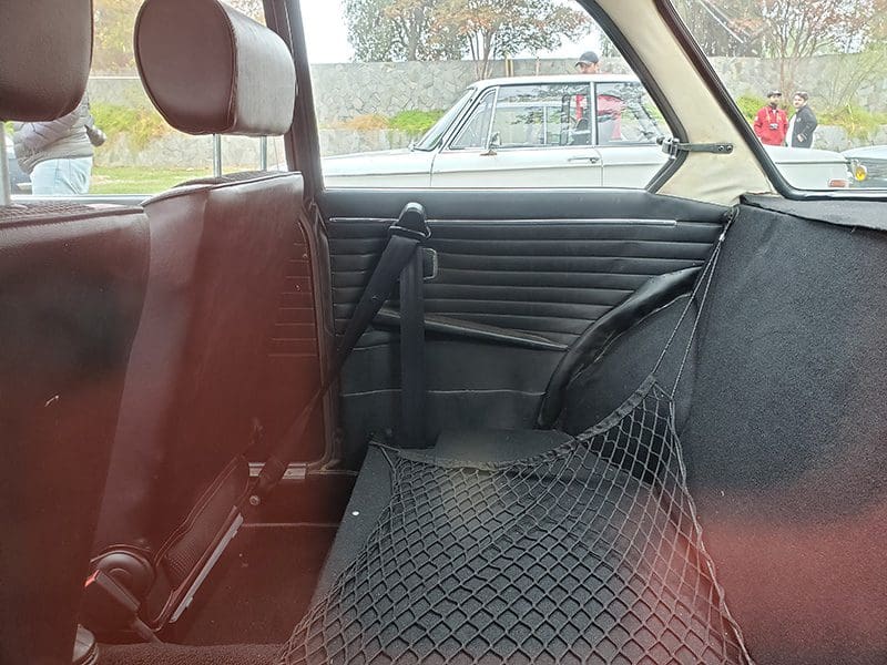 Interior of a vintage car showing red seats and a mesh net on the back seat.