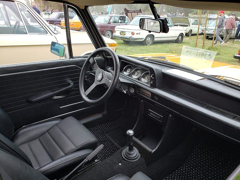Interior of a classic car with a manual transmission and black upholstery.