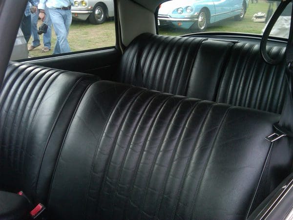 Close-up of black leather car seats inside a vintage vehicle.