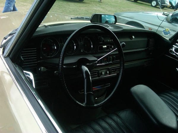 Classic car interior with vintage dashboard and steering wheel.