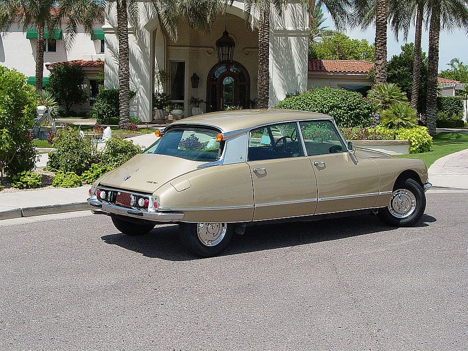 Vintage beige Citro&euml;n DS parked outside a building with palm trees.