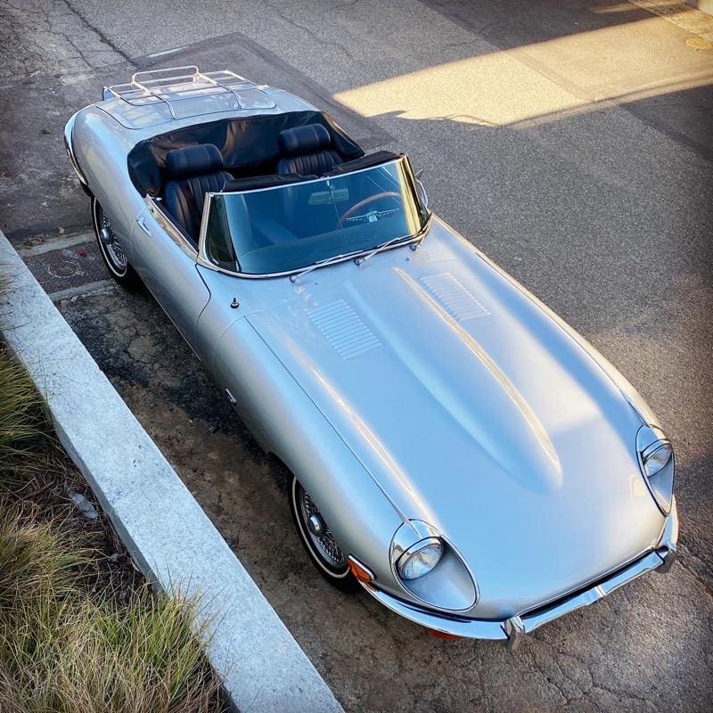 Classic silver convertible sports car parked by the curb.