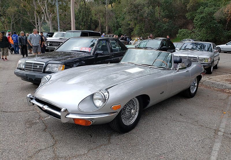 Classic silver Jaguar E-Type convertible parked outdoors.