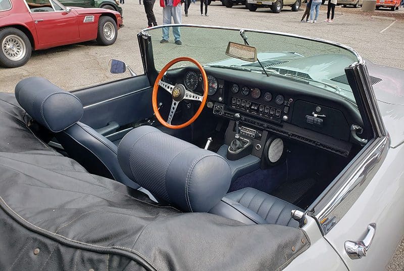 Interior of a classic convertible car with a wooden steering wheel.