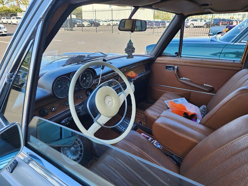 Interior view of a vintage car with a classic steering wheel and brown seats.