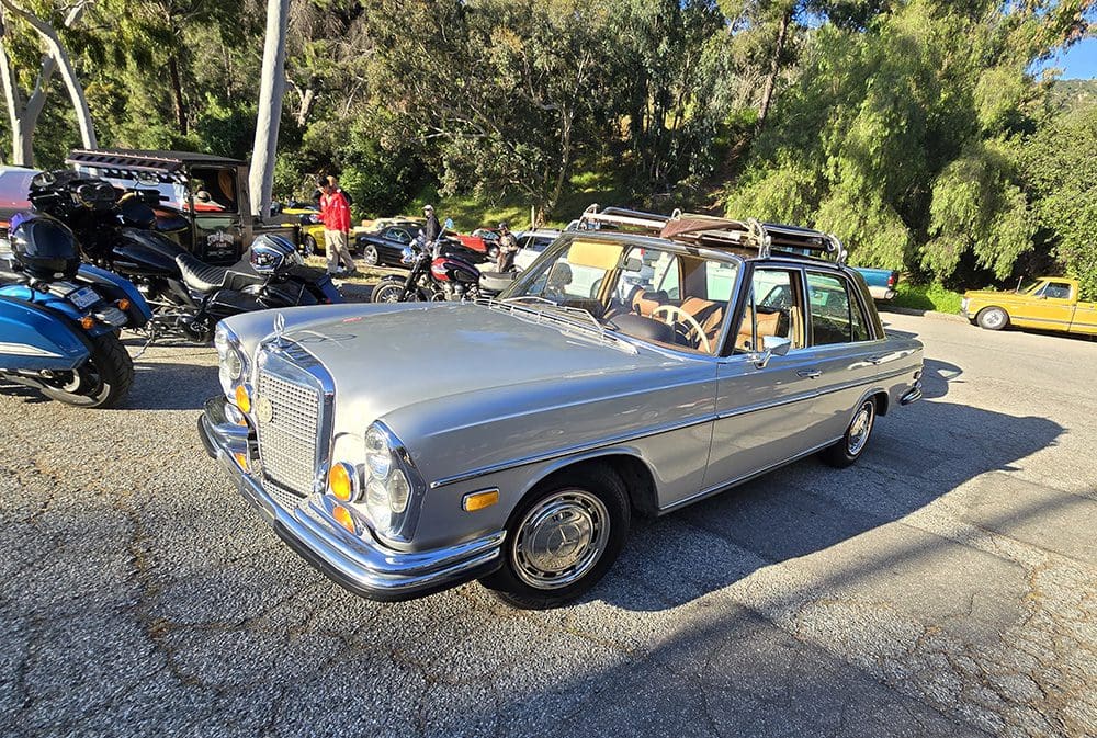 Classic silver Mercedes-Benz convertible parked with people nearby.