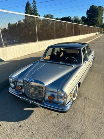 Classic silver Mercedes-Benz parked outdoors on a sunny day.
