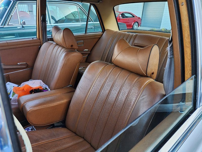 Vintage car interior with brown leather seats and classic design.