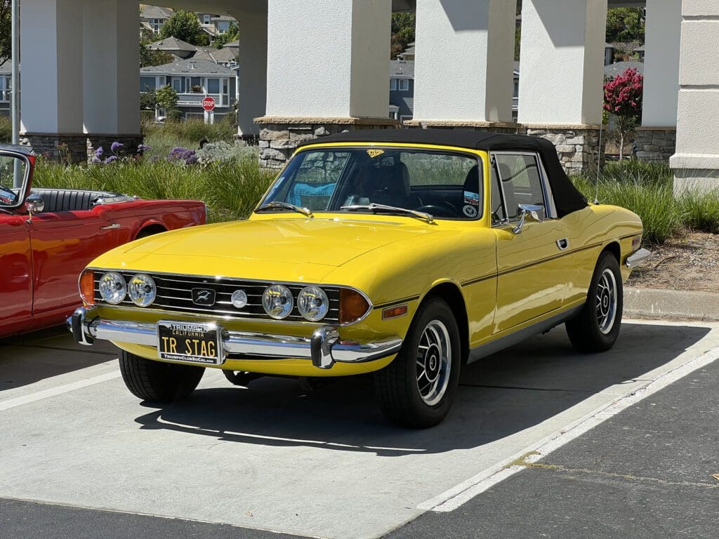 Yellow vintage convertible car parked outdoors on a sunny day.
