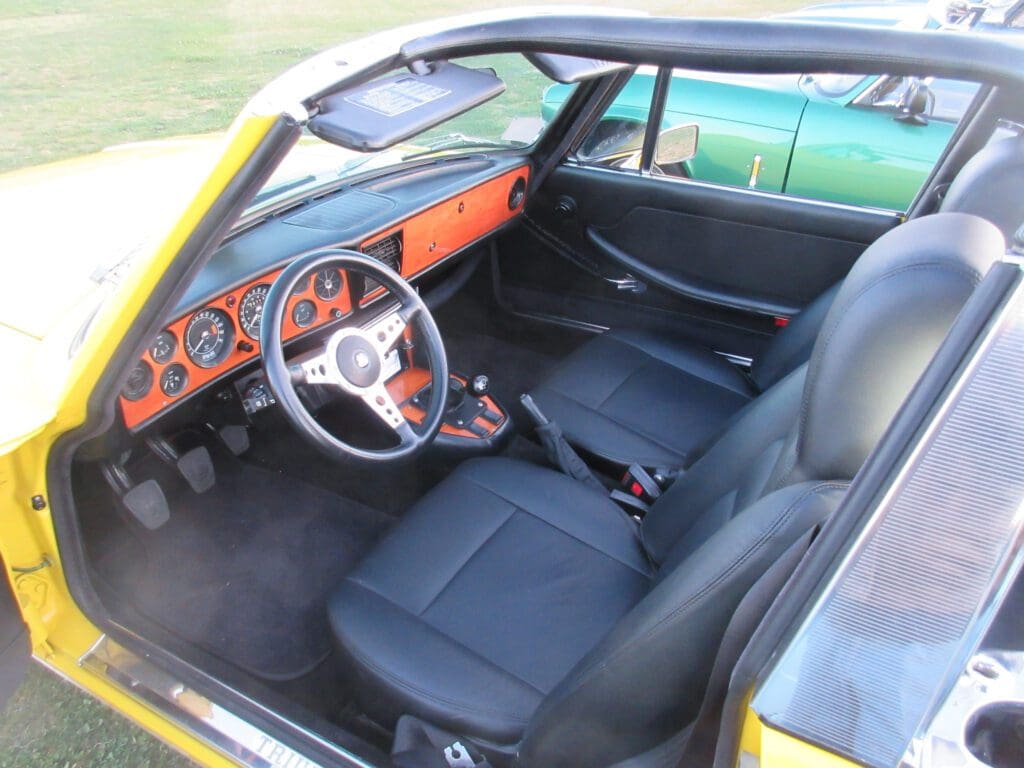 Classic car interior with wooden dashboard and black seats.